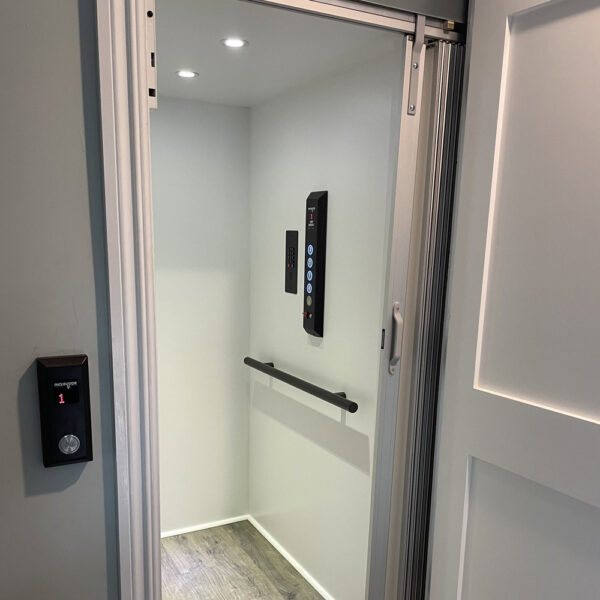 Crown Elevator New Jersey home elevator with white interior, gray driftwood flooring and black control panel and handrail